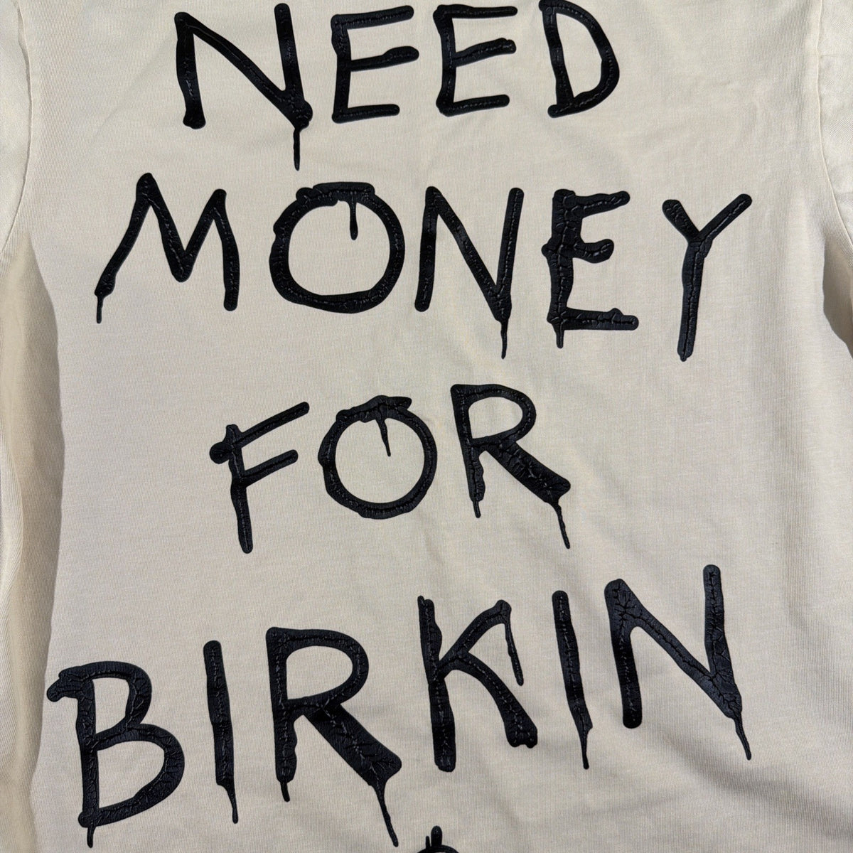 SMAKER cream-colored t-shirt features the graphics NEED MONEY FOR BIRKIN - Fashi