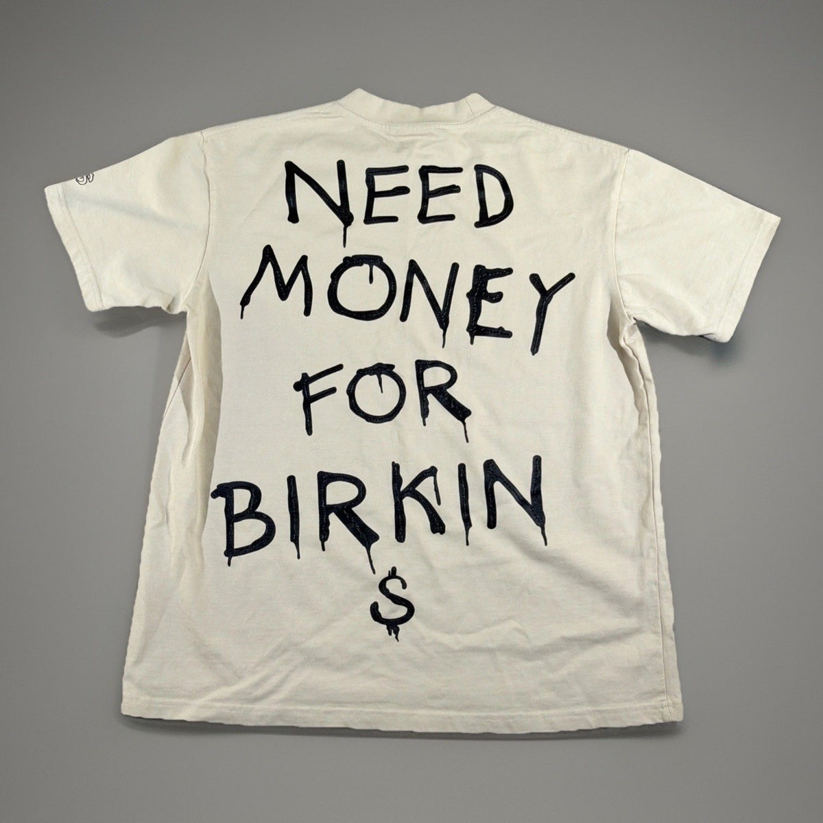 SMAKER cream-colored t-shirt features the graphics NEED MONEY FOR BIRKIN - Fashi