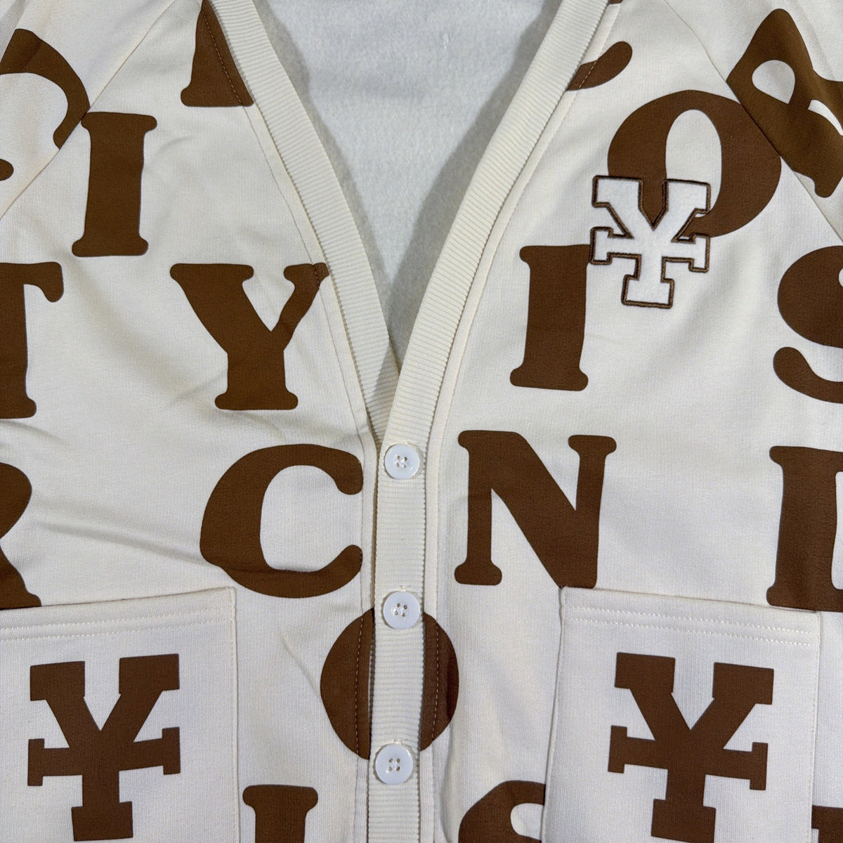 DirtyCoins brand cardigan featuring a distinctive all-over letter pattern
