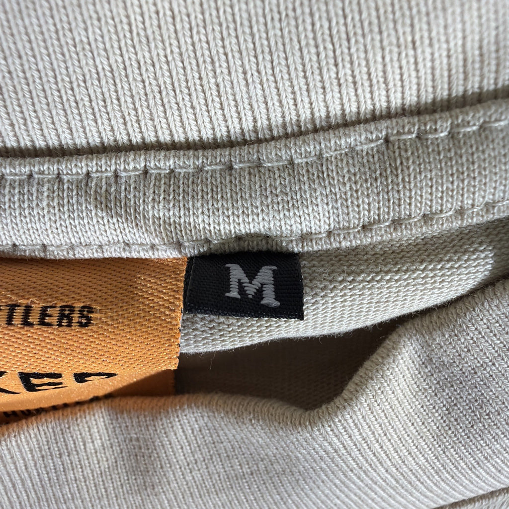SMAKER cream-colored t-shirt features the graphics NEED MONEY FOR BIRKIN - Fashi
