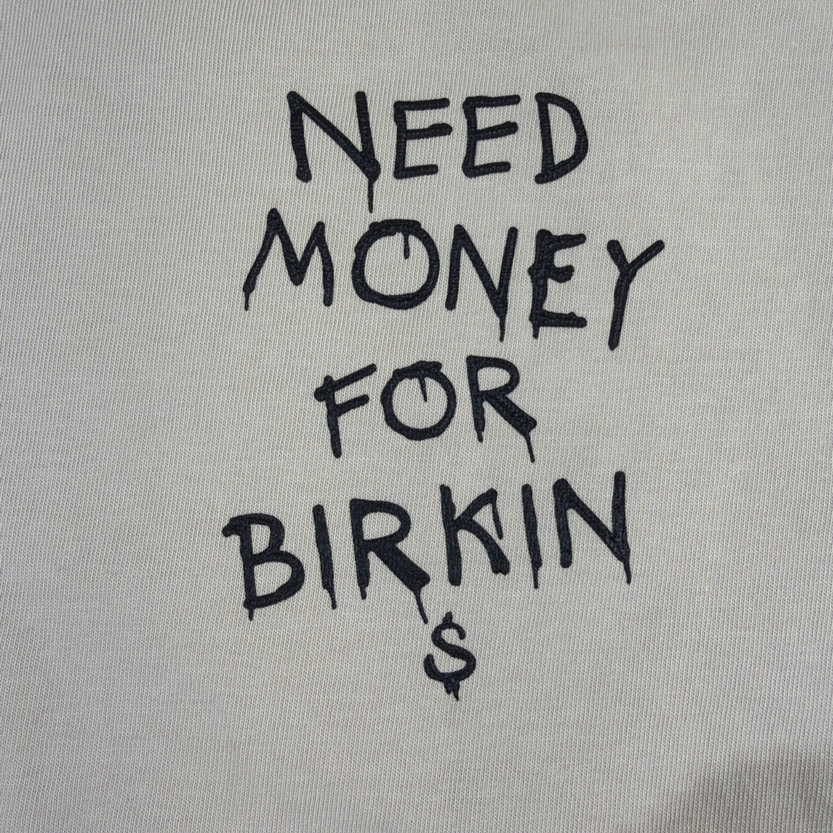 SMAKER cream-colored t-shirt features the graphics NEED MONEY FOR BIRKIN - Fashi