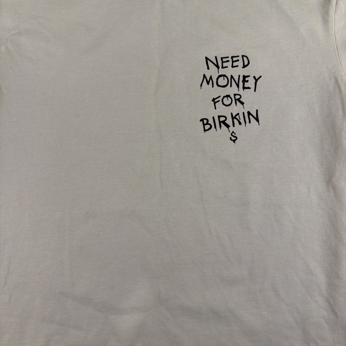 SMAKER cream-colored t-shirt features the graphics NEED MONEY FOR BIRKIN - Fashi